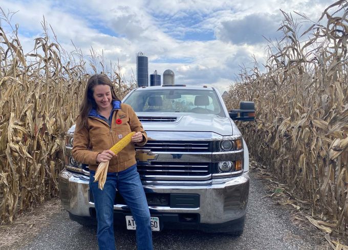 Harvex employee with corn by truck and wheat field