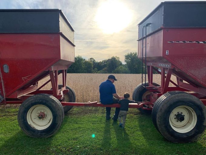 Family sitting on trailers with sunset in the background Harvex